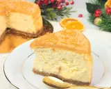 Pyszny sernik piernikowy z karmelem i złotymi kuleczkami, udekorowany na talerzu, w tle świąteczne ozdoby.