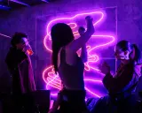Ludzie bawią się przy modnych piosenkach w klubie z neonowym oświetleniem.