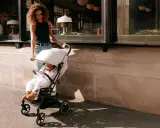 Kobieta prowadzi dziecko w wózku Cybex Beezy ulicą.
