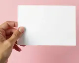 Dłoń trzyma białą kartkę, idealną na zaproszenie na imprezę firmową.