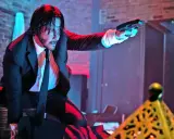John Wick i svart kostym, med pistol i hand, redo för strid. Kanske en scen från John Wick 5.