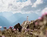 Una mujer en la cima de una montaña rocosa, disfrutando de las vistas. ¡Una gran idea de qué hacer en Cerler en verano!