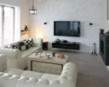 Nowoczesny salon z sofą i stolikiem kawowym. Ściana z białej cegły aranżacje dodaje wnętrzu charakteru.