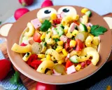 Bunter Nudelsalat mit Mais, Tomaten, Gurken und Schinkenwürfeln in einer Affen-Schüssel – perfekt für Kinder!