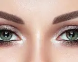 Ojos verdes deslumbrantes con un maquillaje ahumado y brillante, realzando su belleza natural.