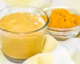 Sauce curry onctueuse dans un verre, avec une coupelle de poudre de curcuma à côté. Parfait pour relever vos plats.