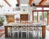 Tavolo rustico con sedie bianche, ideale per un agriturismo ristorante Trento e dintorni. Luce naturale da grandi vetrate.