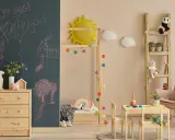 Ein gemütliches Montessori Kinderzimmer für 5-Jährige mit Tafelwand, Holzmöbeln, Spielzeug und einer Leiter als Regal.