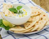 Un bol de tzatziki crémeux garni d'herbes fraîches, servi avec des morceaux de pain pita croustillants. Parfait pour tremper !