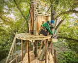 Mann baut Baumhaus für Kinder. Tolle baumhaus kinder ideen für Abenteuer im Grünen.