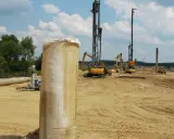 Construcción en terreno arenoso, con maquinaria pesada y tuberías. Se aprecian varios tipos de suelos blandos, listos para la obra.