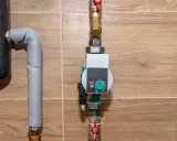 Nowoczesna pompa cyrkulacyjna a obiegowa z cyfrowym wyświetlaczem i pokrętłem regulacji, zamontowana na rurach instalacji grzewczej.