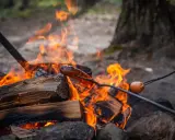 En korv grillas över en sprakande eld. En härlig eld brasa som värmer och ger mat.