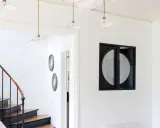 Entrée lumineuse avec escalier aux marches en bois et contremarches noires. Quelle couleur pour une entrée avec escalier ? Ici, le blanc éclatant met en valeur le design.