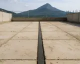Juntas de dilatación en hormigón, con un paisaje montañoso al fondo.