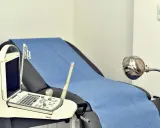 Gabinet lekarski z kozetką, aparaturą USG i lampą. Wczesne wykrycie chorób wenerycznych objawy to klucz do zdrowia.