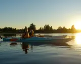Två kvinnor i kajak njuter av solnedgången vid en sjö nära Karlstad.