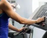 Frau stellt Steigung für ihr **incline walking** auf dem Laufband ein.