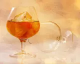 Kieliszek z brandy i lodem, obok pusty, przewrócony kieliszek. Idealny sposób, jak pić brandy.