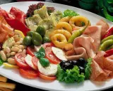 Eine üppige Platte mit italienischen Vorspeisen: Prosciutto, Salami, Mozzarella, Tomaten, Oliven, Artischocken, Bohnen und eingelegte Paprika.