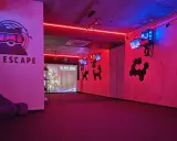 Częstochowa escape room z neonowym oświetleniem, logo VR ESCAPE i ekranem projekcyjnym.