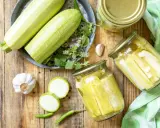 Zucchini haltbar machen: Frische Zucchini, Knoblauch, Chili und Kräuter für die Konservierung in Gläsern.