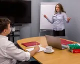 Kobieta tłumaczy mężczyźnie zasady czynnego żalu, wskazując na dokumenty i książki prawnicze.