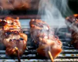 Aromatyczne yakitori skwierczy na grillu, otoczone kłębuszkami dymu.