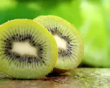 Dwa soczyste kiwi, przekrojone na pół, ukazują swoje zielone wnętrze z czarnymi pestkami. To naturalne kiwi co leczy, pełne witamin.
