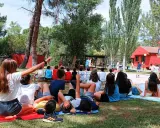 Niños disfrutando de actividades al aire libre en campamentos de verano aula joven. Un grupo observa un partido de baloncesto mientras otros descansan en el césped.