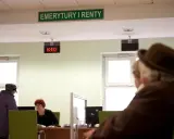 Ludzie czekają na obsługę w urzędzie "Emerytury i Renty". Zastanawiają się, w jakim miesiącu najlepiej przejść na emeryturę.