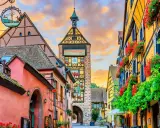 Un pueblo de cuento en Alsacia, con casas coloridas, flores y una torre con reloj. ¡Mucho que ver en Alsacia!