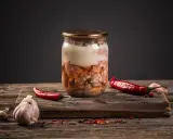 Słoik z mięsem, czosnek i papryczki chili. Przygotowanie tyndalizacji mięsa w piekarniku.