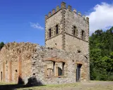 Rovine di un castello con torre merlata, un esempio di cosa vedere a Montecatini Val di Cecina, immerso nel verde.