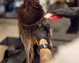 Friseur trägt Farbe auf, um einen sanften Farbverlauf zu erzielen. Die color melting Technik lässt die Töne harmonisch ineinander übergehen.