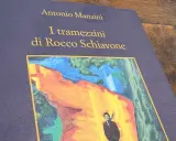 Copertina del **manzini ultimo libro**, "I tramezzini di Rocco Schiavone", con un'illustrazione astratta e un uomo in primo piano.
