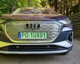 Elegancki, chromowany samochód Audi e-tron z polskimi tablicami rejestracyjnymi stoi na tle zielonego lasu.