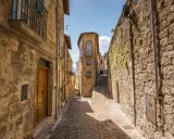 Antica scala di borgo in pietra, con case strette e un cielo azzurro.