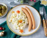 Kartoffelsalat mit Würstchen, dekoriert mit Sternen – ein Klassiker der 10 besten Weihnachtsessen. Dazu gibt es Gewürzgurken und Senf.