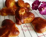 Pan de leche dorado y esponjoso, con forma de corazón, junto a orquídeas moradas. ¡Postres originales para disfrutar!