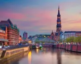 Vacker kvällssol över en kanal i norra Tyskland, med kyrktorn och byggnader som speglas i vattnet.