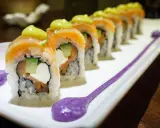 Une délicieuse recette maki original : rouleaux de saumon, avocat, concombre et fromage frais, ornés d'une touche de sauce verte et de purée violette.