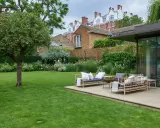 Un prato verde lussureggiante, un patio con mobili in bambù e un giardino fiorito offrono splendide idee giardino per un'oasi urbana.