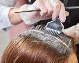 Profesjonalne farbowanie odrostów. Rękawiczki i pędzel z farbą precyzyjnie nakładają produkt na skórę głowy.