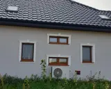 Elegancki gzyms co to? Ozdobne obramowanie okien na szarym domu z brązowymi oknami i słonecznikami.