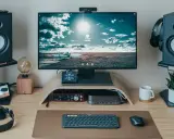 Un bureau moderne pour le setup teletravail : écran, enceintes, clavier, souris, casque et une webcam.