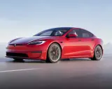 Une Tesla Model S Plaid rouge vif file sur une route côtière, le soleil se reflétant sur sa carrosserie élégante.