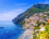 Färgstarka hus klättrar uppför bergssluttningen vid en livlig strand. Perfekt för din resa till Italien tips!