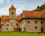 Czerwony Klasztor z wieżą zegarową i pomarańczowymi dachami. Sprawdź cennik zwiedzania tego zabytku.
