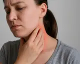 Donna con mano sul collo arrossato, prova dolore alla pelle che fa male sfiorandola.